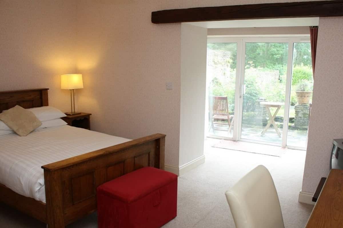 Ein Schlafzimmer mit einem hölzernen Bett, einer roten Bank, einem Sessel und einem Balkon mit Tisch und Stühlen.
