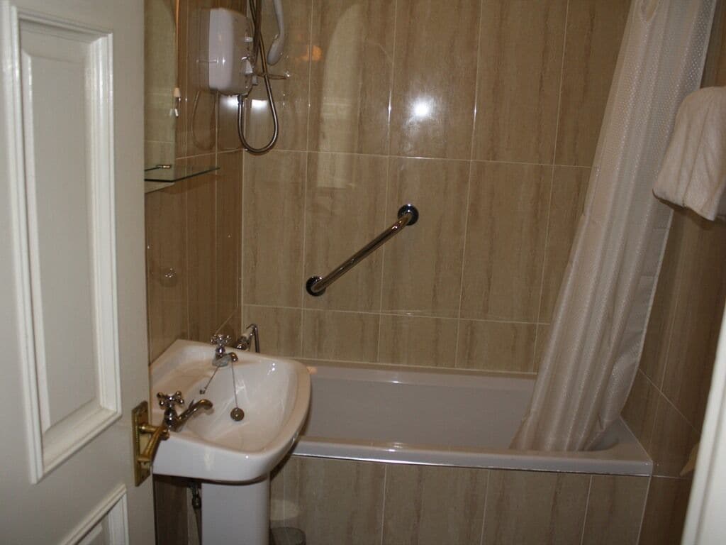 Une salle de bain équipée d’un lavabo, d’une douche et d’une barre d’appui.