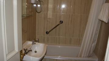 Une salle de bain équipée d’un lavabo, d’une douche et d’une barre d’appui.