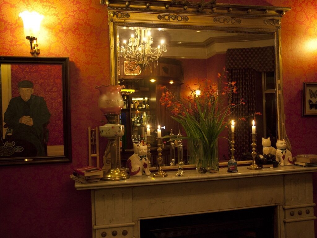 A fireplace mantel with various decorative items, a mirror, and a framed picture on the wall.
