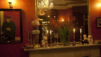 A fireplace mantel with various decorative items, a mirror, and a framed picture on the wall.