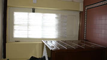A room with a wooden foosball table, a window with lace curtains, and a wall with a patterned tile border.