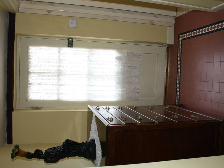 A room with a wooden foosball table, a window with lace curtains, and a wall with a patterned tile border.