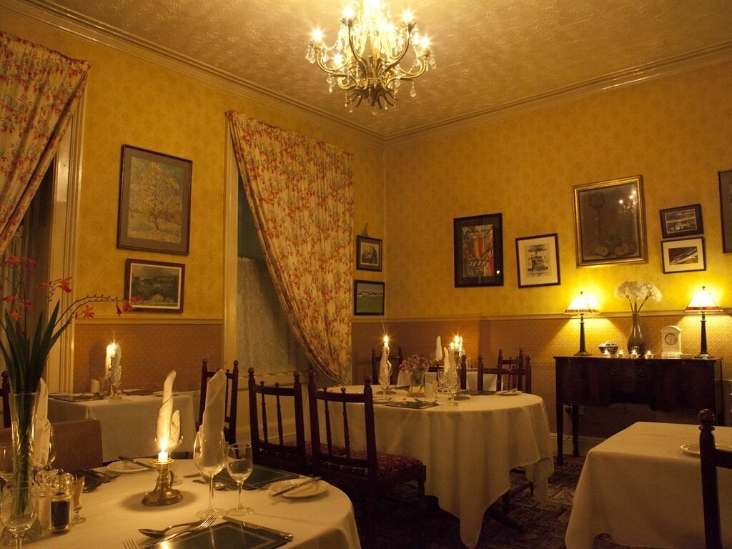 A dining room with round tables, candles, and framed pictures on the walls.