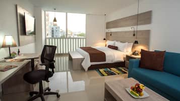 Habitación de hotel moderna con cama, escritorio, silla, sofá y vistas a la ciudad.