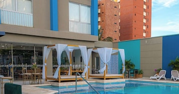 Un área de piscina con sillones de descanso y una cabaña.