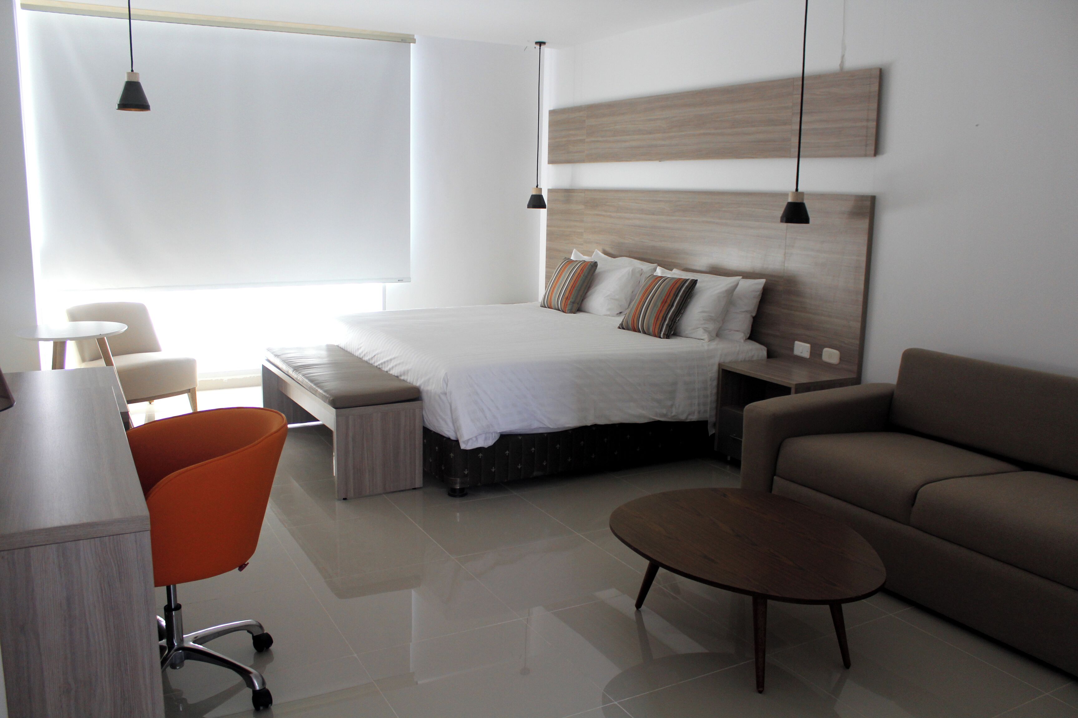Een moderne slaapkamer met een bed, een bank, een bureau en een stoel.