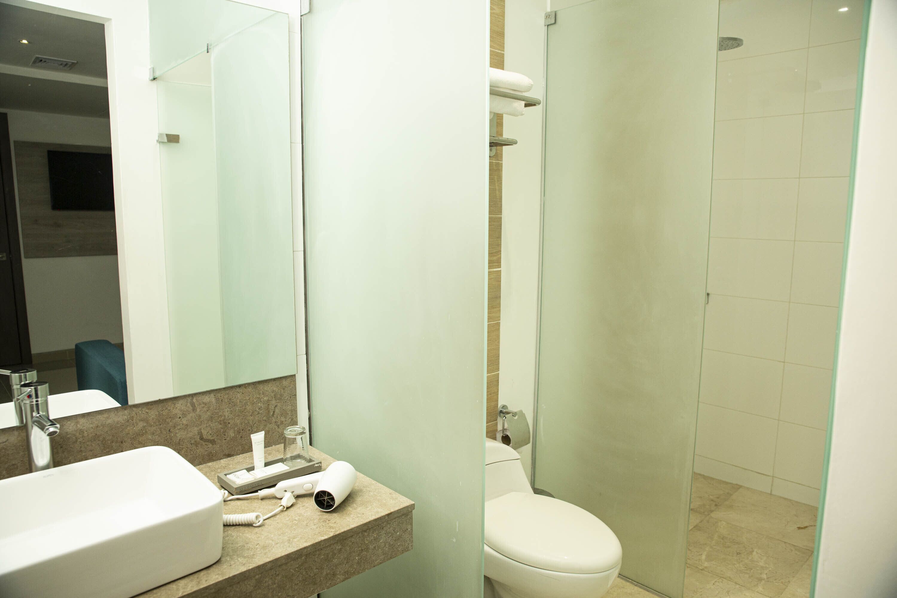 Un baño moderno con un lavamanos grande, un inodoro y una ducha con mampara de vidrio.