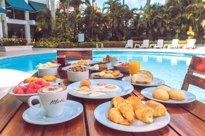 A breakfast buffet by a poolside with various dishes and a coffee cup labeled "Mali". - Hotel Barranquilla Plaza (Barranquilla)