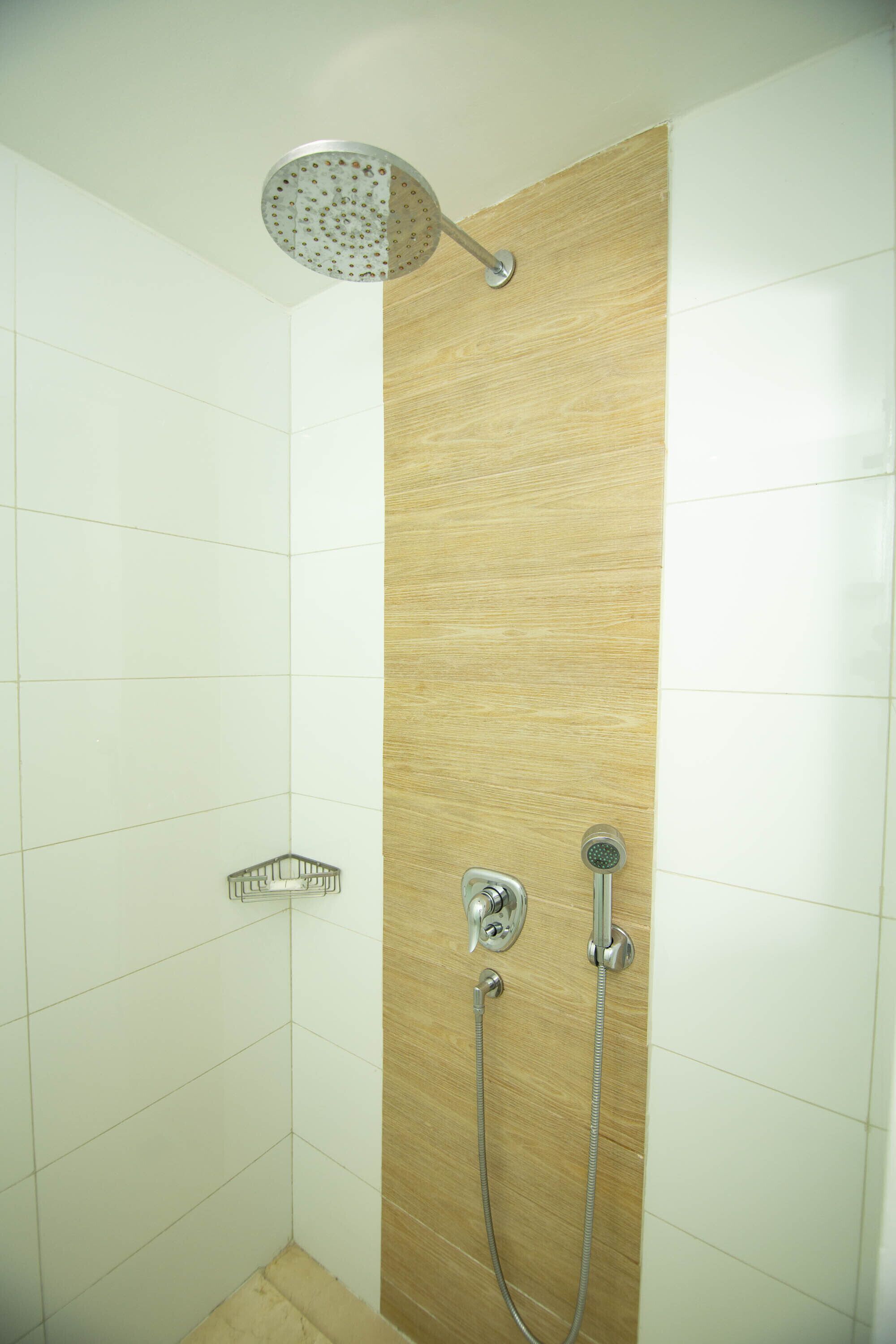 A shower with a handheld showerhead and a wall-mounted faucet.