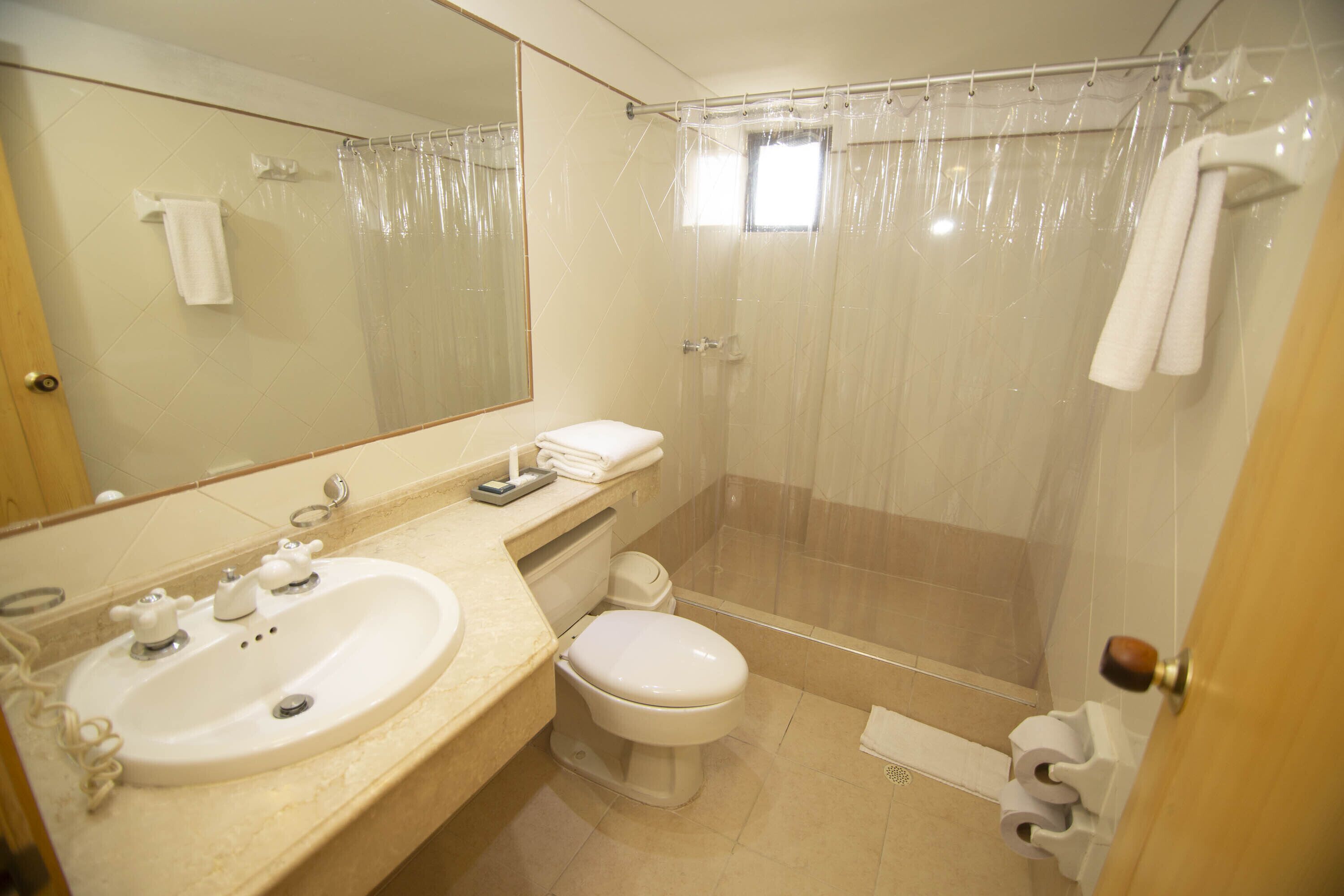 Une salle de bain avec un lavabo, des toilettes et un rideau de douche.