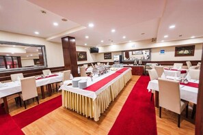 A conference room with tables set for a meeting, a buffet area, and a television screen on the wall. - Astra Old Town (Sarajevo)