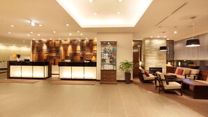 Amplio vestíbulo con recepción, zona de estar y pared decorativa con diversos diseños.