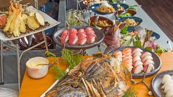 A variety of seafood dishes including grilled fish, sashimi, and tempura on a buffet table.