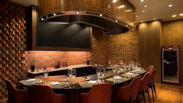 Un comedor moderno con pared de ladrillo, techo de madera curvada y un enfriador de vinos.
