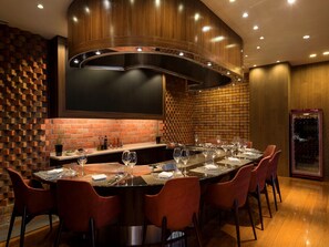 Un comedor moderno con pared de ladrillo, techo de madera curvada y un enfriador de vinos.