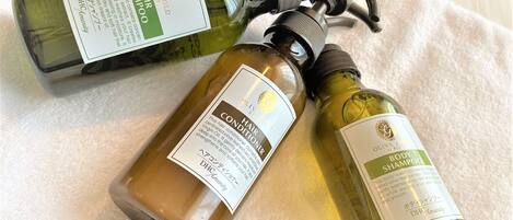 Tres botellas de acondicionador y champú sobre una toalla blanca.
