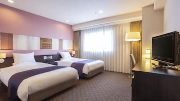 A hotel room with two beds, a desk with a TV, and a window with curtains.