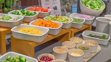 Una mesa de buffet con diversos alimentos, como ensaladas, verduras y granos.