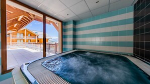 A hot tub with a view of a wooden building and a tiled wall. - Noemys Les Chalets de Bois Méan (Les Orres)