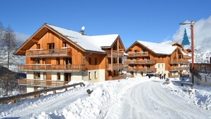 A wooden chalet-style hotel with multiple balconies and a snow-covered driveway. - Noemys Les Chalets de Bois Méan (Les Orres)