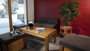 A cozy room with a wooden table, a grey sofa, and a large potted plant. - Noemys Les Chalets de Bois Méan (Les Orres)