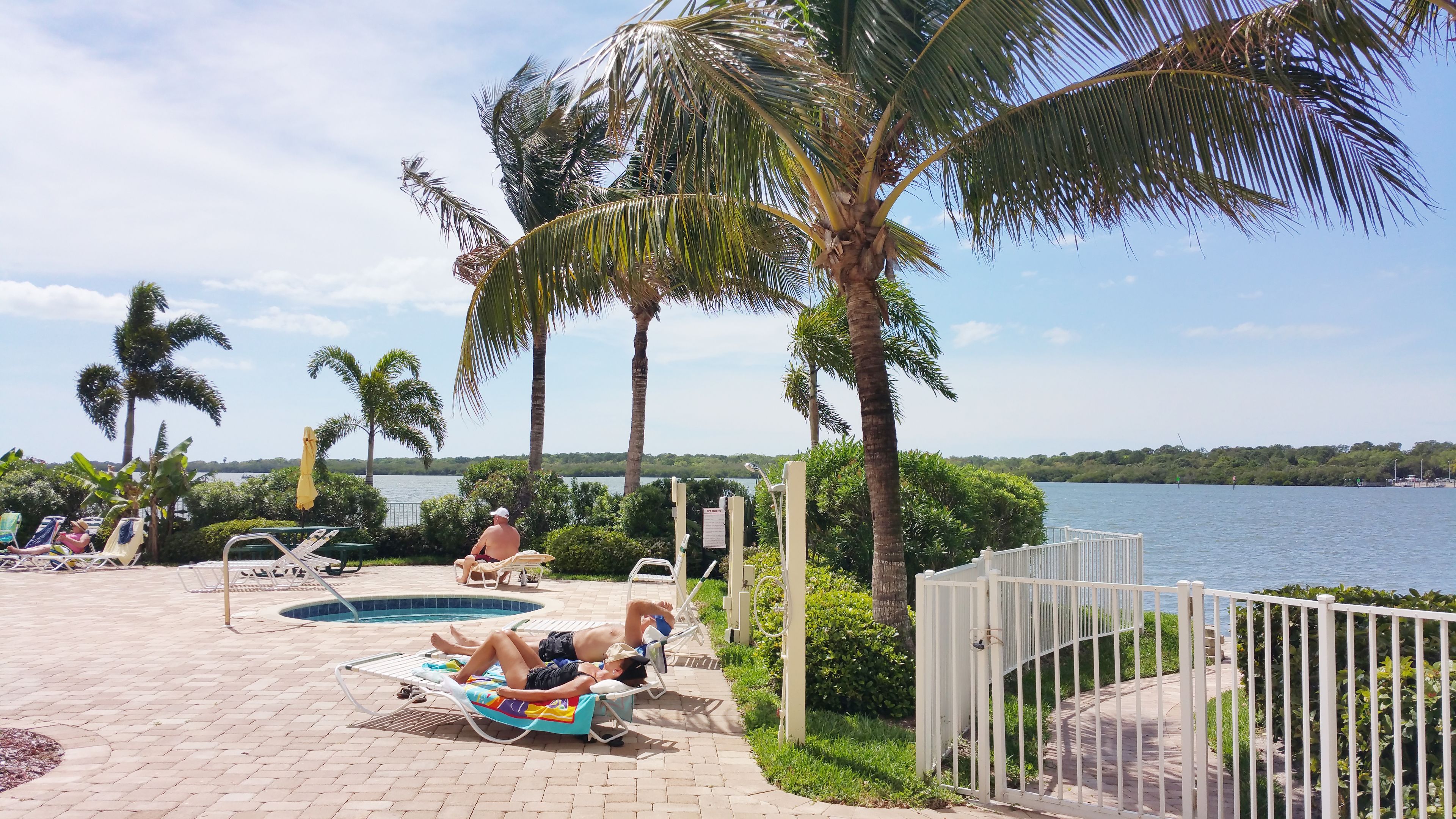 A poolside area with lounge chairs, a swimming pool, and a view of a lake.