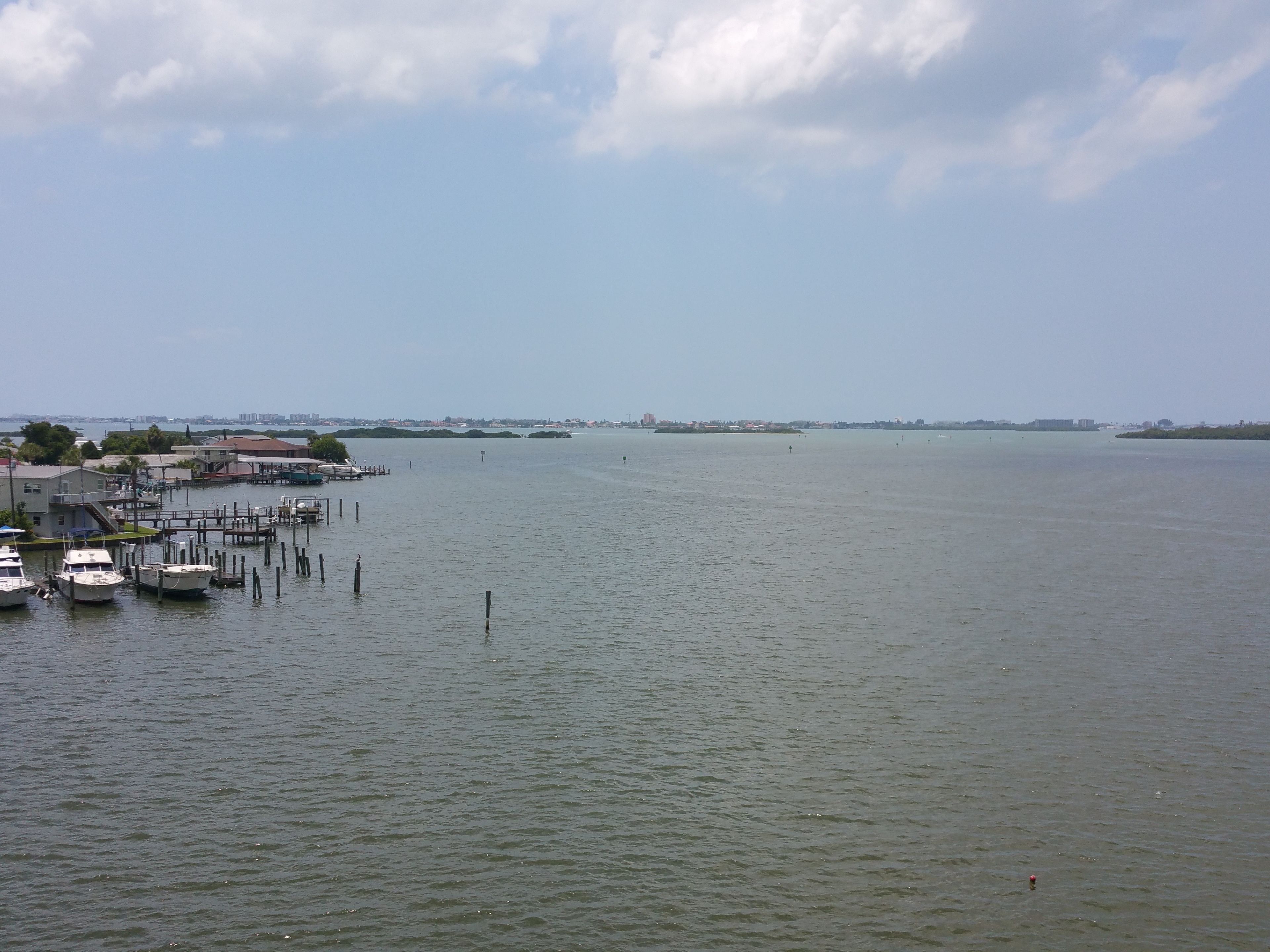 Un port de plaisance avec des bateaux amarrés et une vue dégagée sur la côte lointaine.