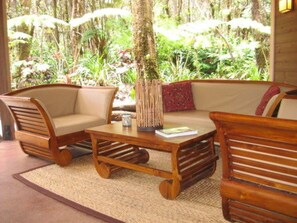 A wooden sofa set with a woven rug, a small table, and a vase with a red cushion.