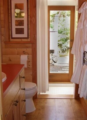 A bathroom with wooden cabinetry, a toilet, and a shower area.