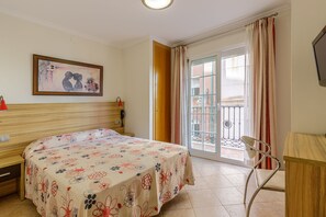 A hotel room with a bed, a desk, a chair, a painting on the wall, and a balcony with a view. -  HA Hotel Trebol (Málaga)