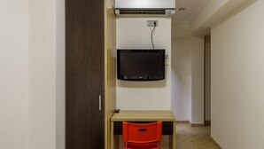A room with a wooden desk, a red chair, a flat-screen TV, and an air conditioning unit mounted on the wall. -  HA Hotel Trebol (Málaga)