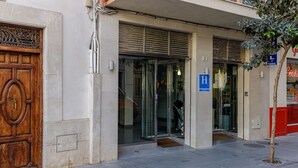 A building entrance with a wooden door, glass doors, and a blue handicap accessibility sign. -  HA Hotel Trebol (Málaga)
