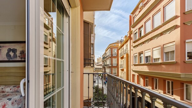 A narrow street with buildings on either side, a balcony with a metal railing, and a view of the street below. -  HA Hotel Trebol (Málaga)