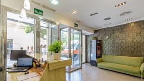 A reception area with a desk, computer, and a green sofa. -  HA Hotel Trebol (Málaga)