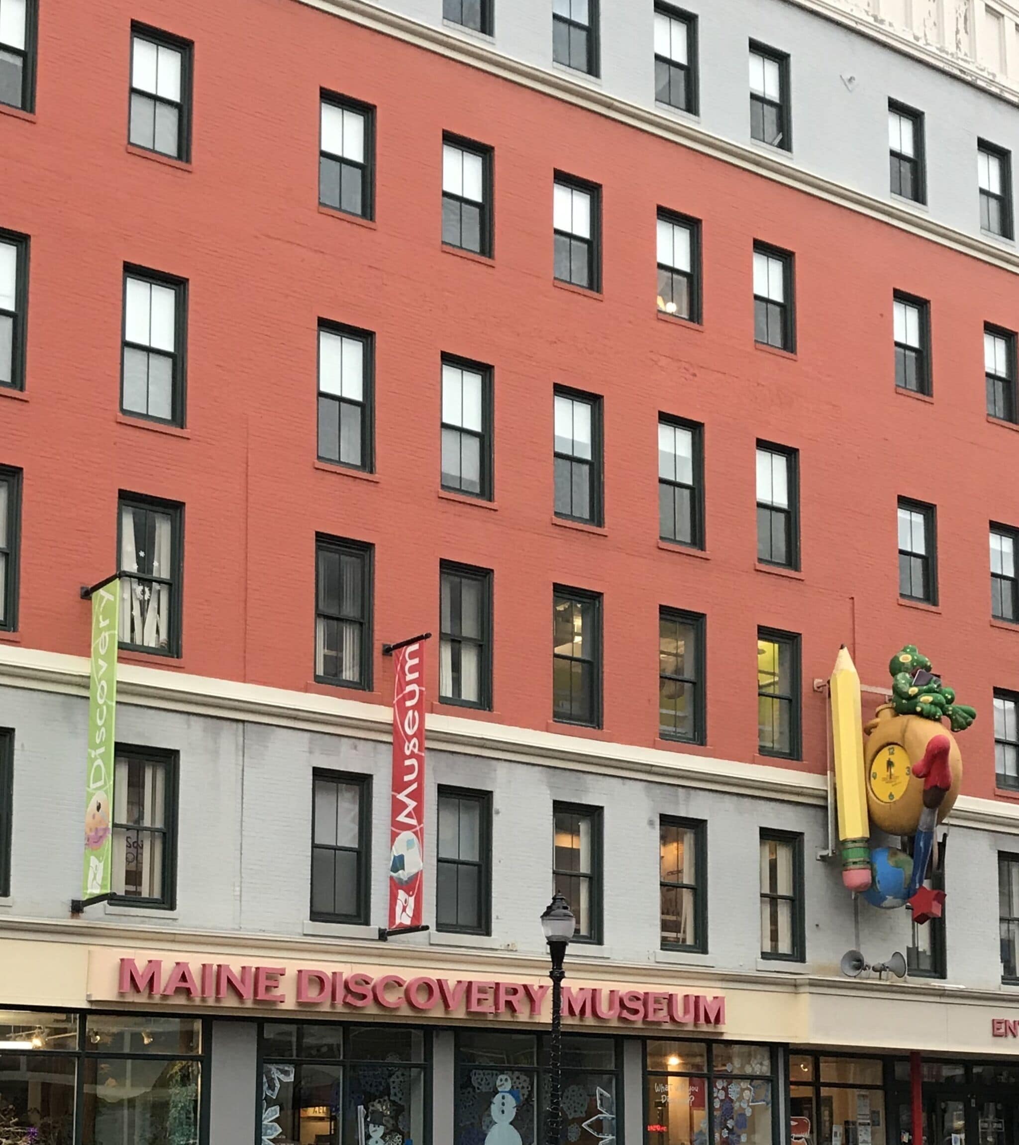 The exterior of the Maine Discovery Museum with a red facade and multiple windows.