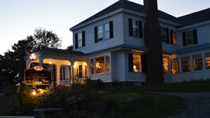 A two-story house with a porch and a sign that reads "The Brewster Inn."