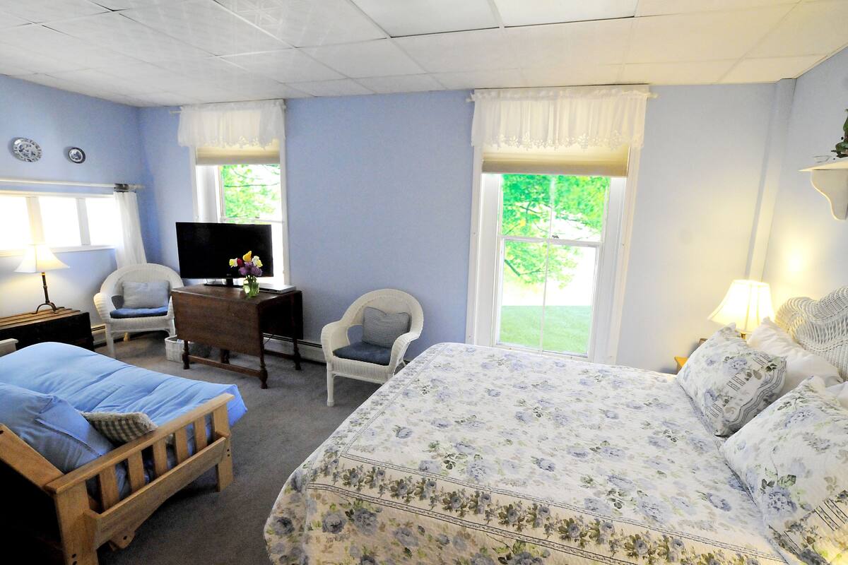 A bedroom with a bed, a chair, a TV, and a desk.