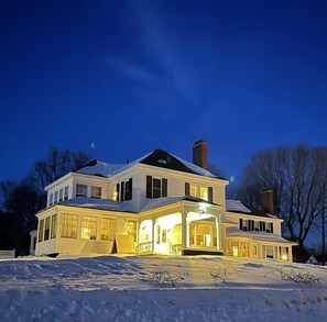 A large, two-story house with a covered front porch and a chimney.