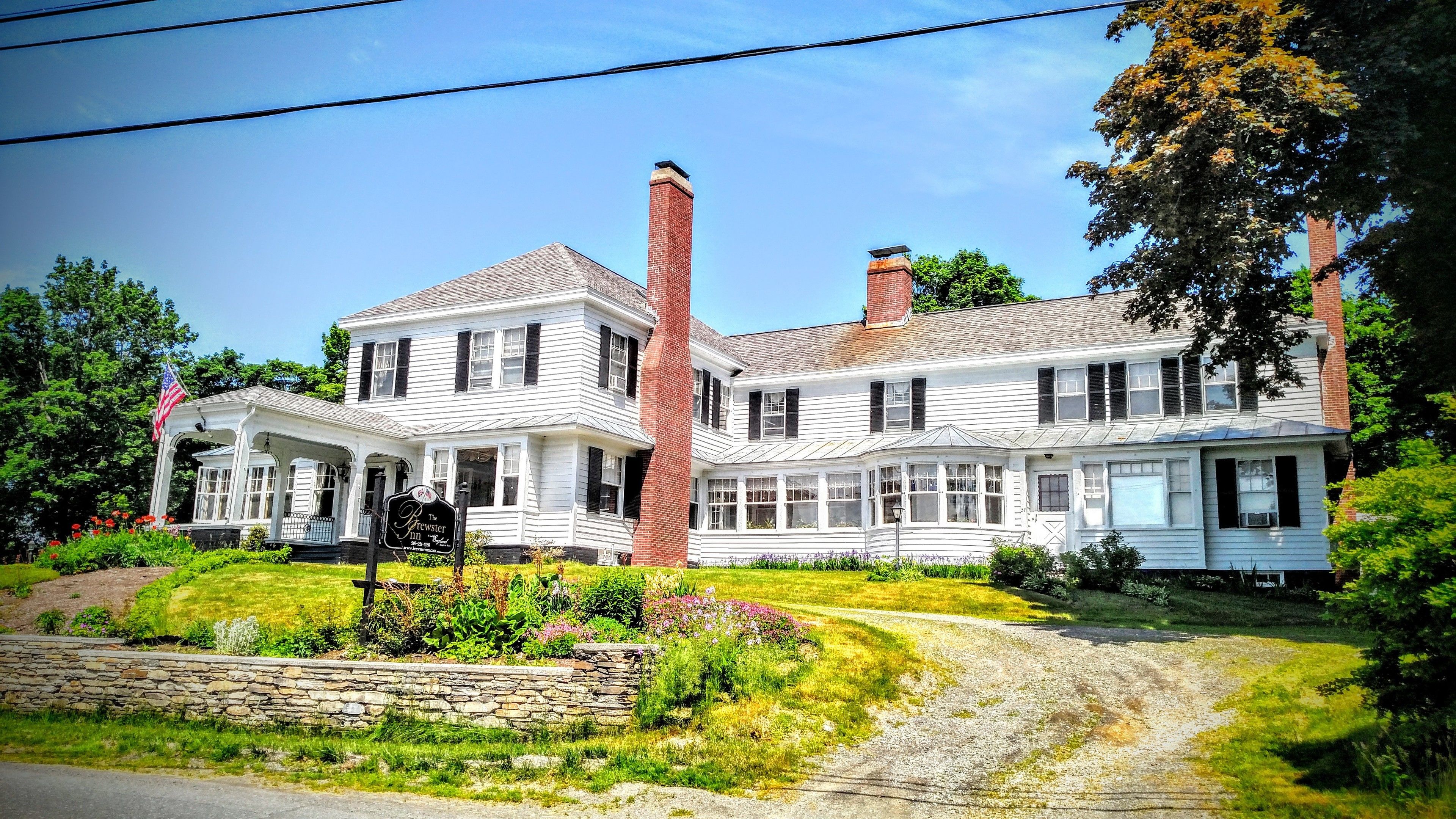 Un bâtiment à deux étages doté d’un porche, d’une enseigne indiquant qu’il s’agit de « The Brewster Inn », et d’un mur de pierre au premier plan.