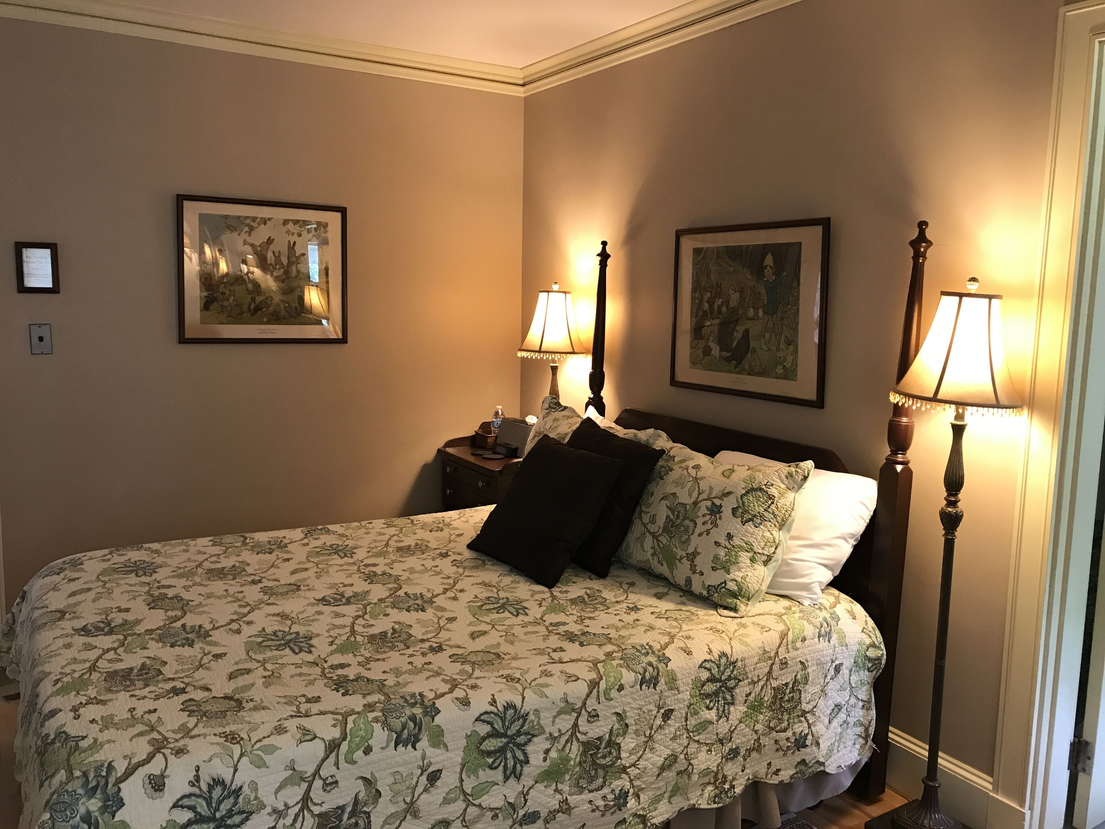 Camera d'albergo con un letto grande, due comodini, due lampade a parete e due quadri appesi alle pareti.