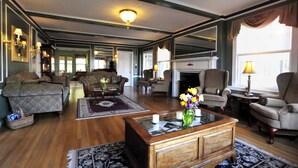 A spacious living room with a fireplace, multiple seating areas, and a large mirror reflecting the room. - Brewster Inn (Dexter)