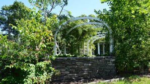 A stone wall with a white archway surrounded by lush greenery.