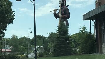 Una estatua de un hombre sosteniendo un horcón en un parque, con un edificio al fondo.