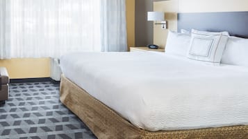 Una habitación de hotel con una cama grande, una mesita de noche con lámpara y un suelo estampado.