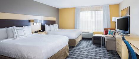 Quarto de hotel com duas camas, uma escrivaninha, televisão e janela com cortinas.