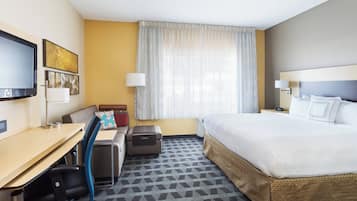 Une chambre d’hôtel équipée d’un lit, d’un bureau, d’une chaise et d’un téléviseur fixé au mur.