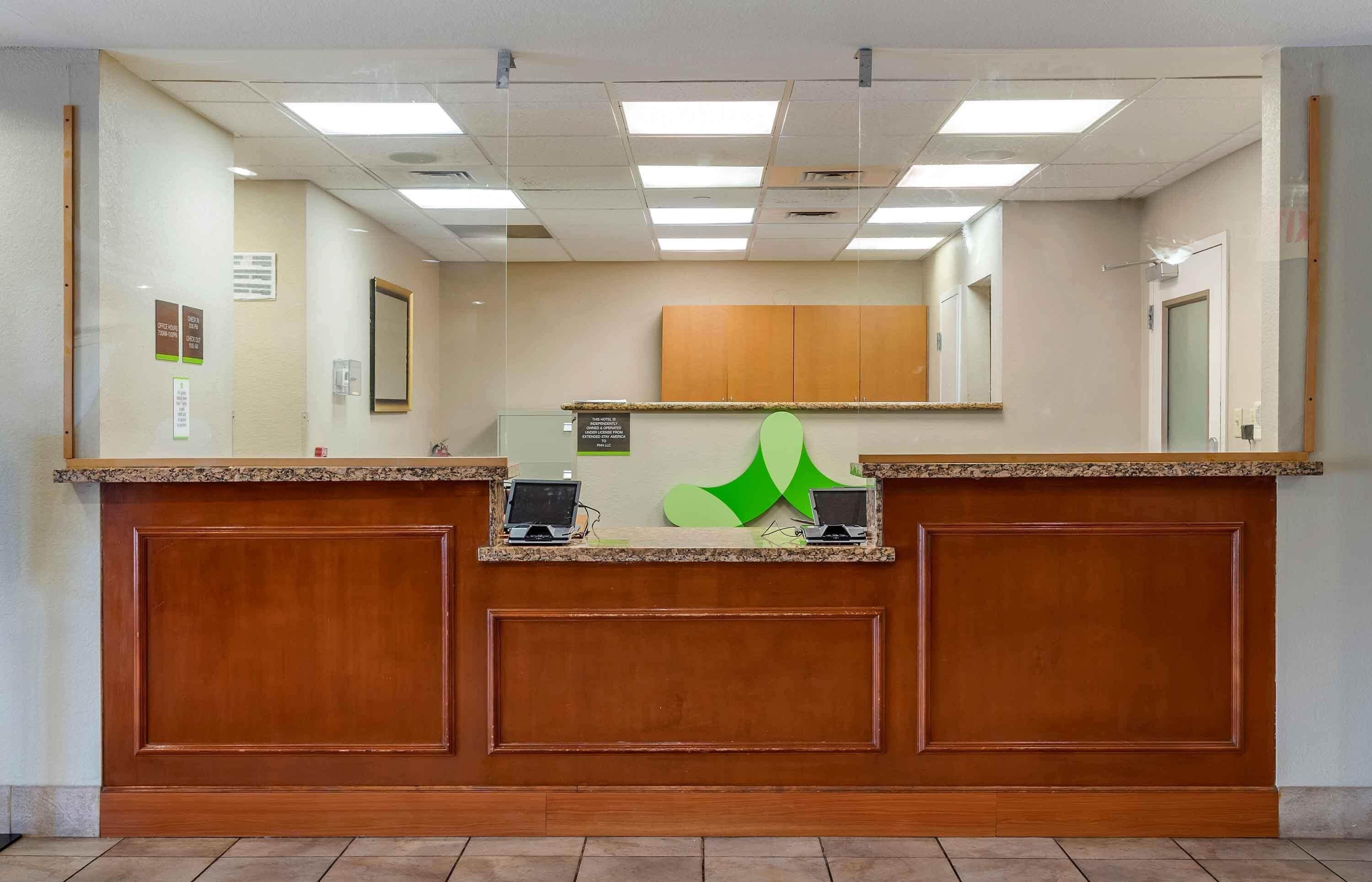 A reception desk with a wooden finish, two computer monitors, and a green logo.