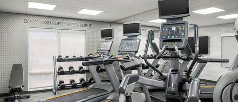 A gym with treadmills, dumbbells, and exercise equipment.