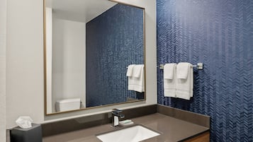 Ein modernes Badezimmer mit einem großen Spiegel, einem Waschbecken und einem Handtuchhalter.